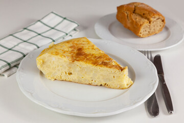 Plato con una ración de la típica tortilla española servido sobre la mesa de un restaurante y listo par comer