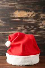 Obraz na płótnie Canvas Single Santa Claus red hat on brown wooden background.