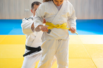 Black belt judoka and young yellow belt judo girl