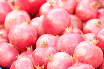 Pile of red ripe pomegranate fruits as background. Heap of tasty fruits close up.