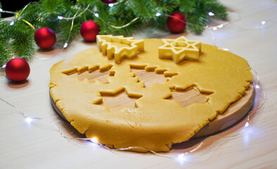 Making traditional Christmas gingerbread and honey cookies. Raw dough with cutters of Christmas tree and star shape, fir branches and toys on background. Homemade bakery, winter holidays entertainment