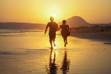 Fototapeta premium KIds running and playing on water on a beach evening time in Mukalla City, Yemen, 2020