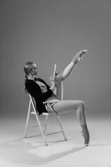 Graceful. Young fashionable, stylish woman wearing jacket and socks working from home. Fashion during insulation 'cause of coronavirus pandemic. Half business and half home style. Black and white.