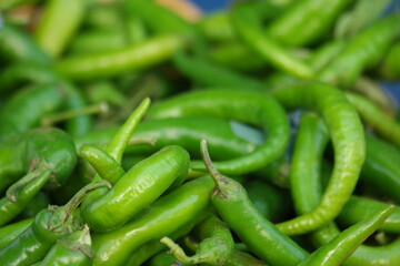 Green hot chili peppers background. Pile of raw spicy vegetables at market stall close up. Organic food industry.