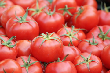 Pile of red ripe tomatoes at grocery store. Tomatoes heap texture. Organic food industry.