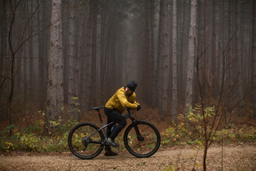 Young man taking a brake during biking through autumn forest