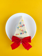 Slice of cheesecake, classic New York style cheesecake. Piece of delicious cake on a white plate, in a Christmas theme