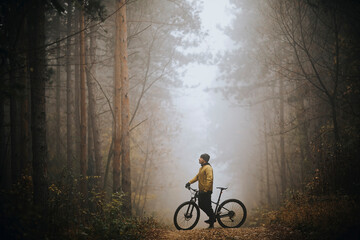 Fototapeta na wymiar Young man taking a brake during biking through autumn forest