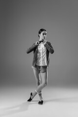 Posing. Young fashionable, stylish woman wearing jacket and socks working from home. Fashion during insulation 'cause of coronavirus pandemic. Half business and half home style. Black and white.