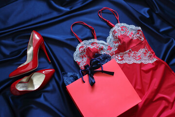 Red silk lingerie and  red shoes on a blue satin  background. Romantic gift for saint valentin day.