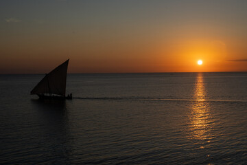 Wooden sailboat on the clear water of Zanzibar island during sunset..