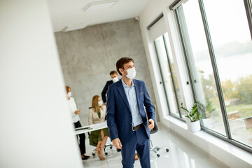 Fototapeta premium Handsome young business man wearing protective facial mask while holdind digital tablet