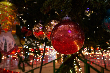 red christmas ball with push-up lights hanging on a christmas tree with garlands