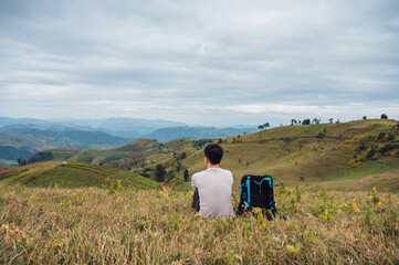 Fototapeta na wymiar Asian man relaxing with camera bag on farmland hill in rural