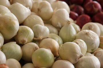 Fresh white onions at the farmers market. Pile of organic vegetables close up.