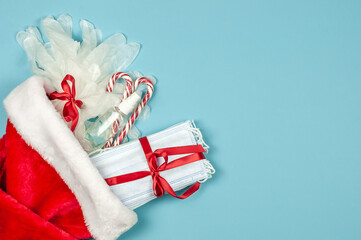 Masks, gloves, antiseptic  in a Santa hat on a blue background.Best gift 2021