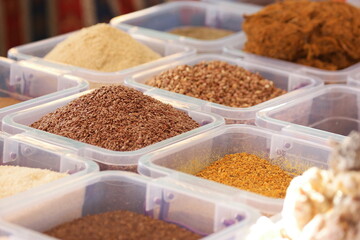 Flax seeds and other healthy seasonings in plastic boxes. Close up of containers with assorted oriental spices.