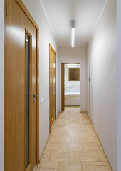 Contemporary interior of hallway in modern apartment. White walls. Opened door to bedroom.