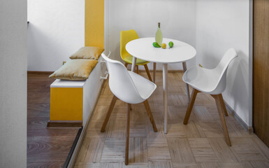 Modern interior of apartment in white and yellow colors. Fruits and liquor on white table. Simple home design.