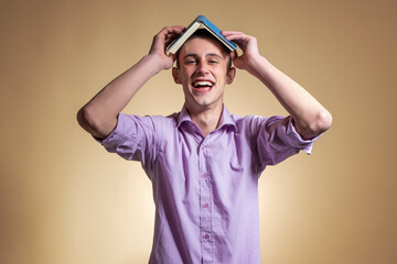 Handsome single teenager with notebook on his head, studio photography