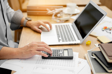 Businessman pressing on calculator for calculating cost estimating with laptop.