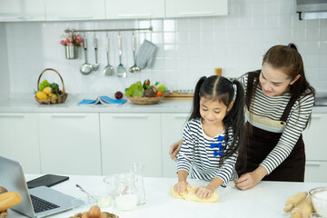 Asian mother and child cook from flour in kitchen,leisure activity at home.