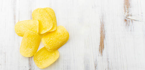 Potato chips on a white wooden background.