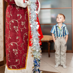 The actor in the role of Santa Claus is invited to the home of a little boy. The distrustful, doubtful look of a child.