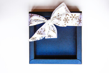 Blue shiny box with a white bow. festive packaging. Christmas decorations on white background . Holiday and celebration. Flat lay, top view