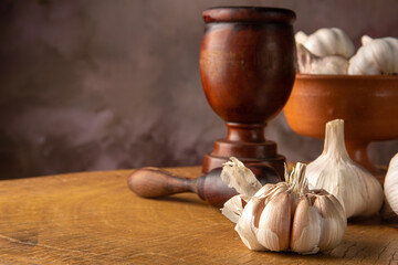 Garlic, arrangement with garlic heads and accessories on rustic wooden surface, abstract background, low key image, selective focus.