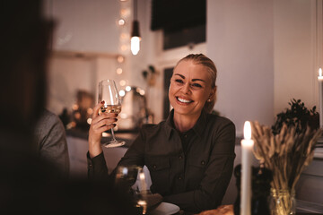 Smiling woman having wine with friends at a dinner party