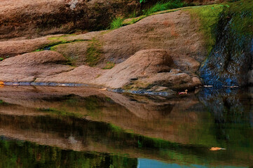 Reflecting stone bank along a still pond