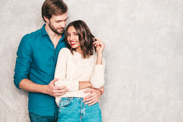Portrait of smiling beautiful woman and her handsome boyfriend. Happy cheerful family posing in studio near gray wall.Valentine's Day. Models hugging. Concept of love