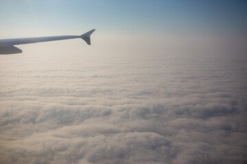 Airplane wings flying in midair and view of clouds in the sky