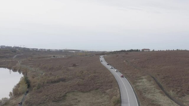 Elli&eth;avatnsvegur road leading into Gar&eth;ab&aelig;r town on cloudy day, aerial