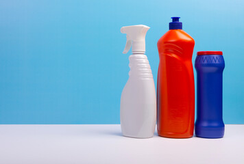 Cleaning concept with various plastic bottles and canisters on blue background. Various detergents and the necessary attributes for cleaning