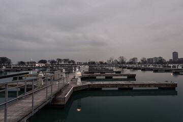 Early evening on a calm lake with wooden walkway leading to empty boat docks in Chicago