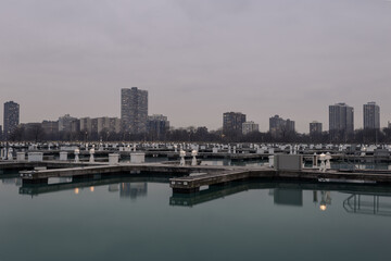 Fototapeta na wymiar Highrise apartment buildings on overcast day behind empty boat docks on calm water in Chicago