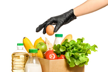 A hand in a black protective glove lays an egg in a cardboard box with food.