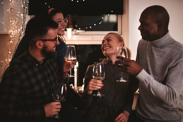 Laughing friends drinking wine and talking together at a party