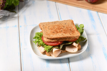 Sandwich with ham and fresh salad on the plate.