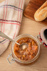 Glass jar with delicious homemade apple and onion chutney, with cinnamon on a light wooden board. Perfect jam for breakfast. Breakfast, cooking, food concept.
