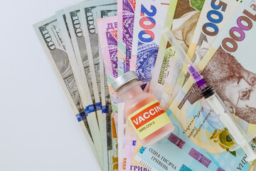 Vaccination against the new CoronaVirus SARS-CoV-2 on medical syringe on US dollar and Ukrainian hryvnia bills