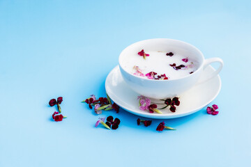 White Cup with vegan milk and flowers on a blue background. Concept of vegetarian drinks and food, herbal teas, beauty and health, Spa