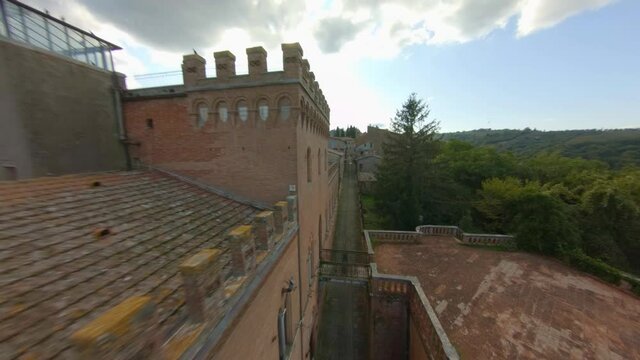 Flock Of Pigeons Flying On Traditional And Brick Buildings In Sinalunga, Siena, Italy. - FPV, Aerial
