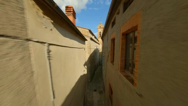 Drone Flying Through Narrow Alley Towards Bell Tower Of Collegiate Church Of San Biagio - Scrofiano, Sinalunga - low aerial ascending