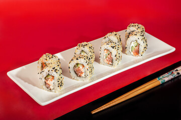 Sushi Sets Nigiri, Uramaki, California, Philadelphia, on a white plate. On a red colored background.
