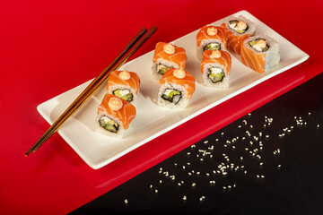 Sushi Sets Nigiri, Uramaki, California, Philadelphia, on a white plate. On a red colored background.