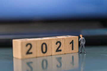 2021 New Year, Business concept. Businessman miniature figure people standing with wooden number block.