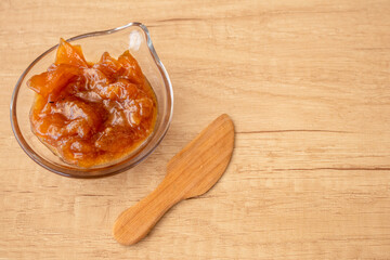 Glass pot with a delicious homemade apple and onion chutney, with cinnamon on a light wooden board....